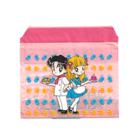 small pink bag featuring an image of an anime girl and anime holding deserts on a field of fruit, specifically pineapples and bananas from the 90s manga Delicious!