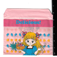small pink bag featuring an image of an anime girl with a pineapple and other fruit from the 90s manga Delicious! next to a black ruler.